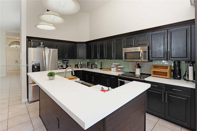 kitchen with pendant lighting, stainless steel appliances, and a center island with sink