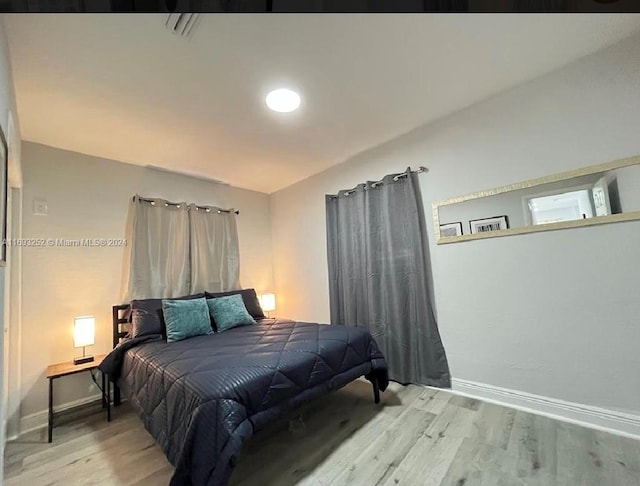 bedroom with lofted ceiling and wood-type flooring