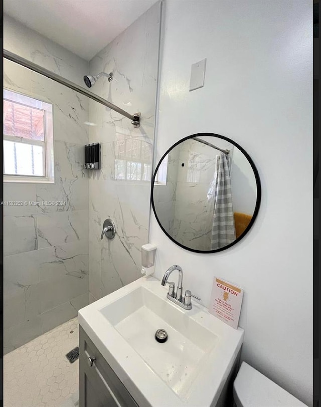 bathroom with vanity, toilet, and tiled shower