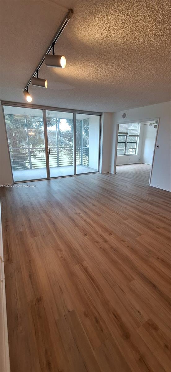 unfurnished living room with track lighting, wood-type flooring, and a textured ceiling