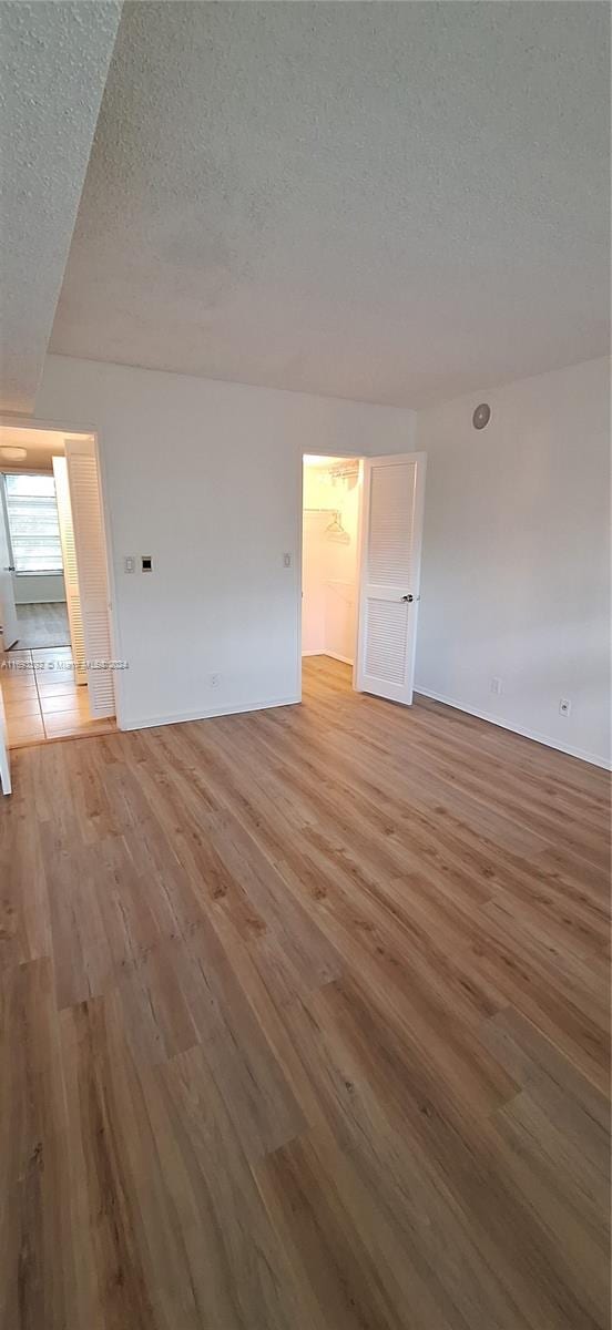 unfurnished room with light hardwood / wood-style floors and a textured ceiling