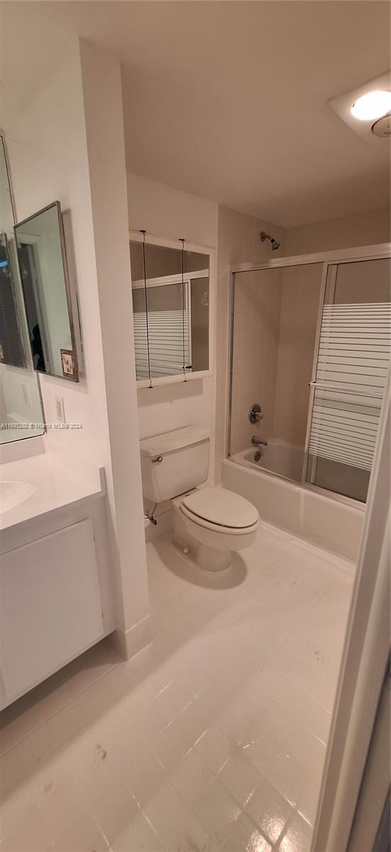 full bathroom featuring tile patterned flooring, vanity, bath / shower combo with glass door, and toilet