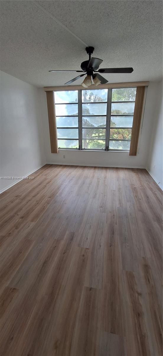 unfurnished room with a healthy amount of sunlight, a textured ceiling, and wood-type flooring