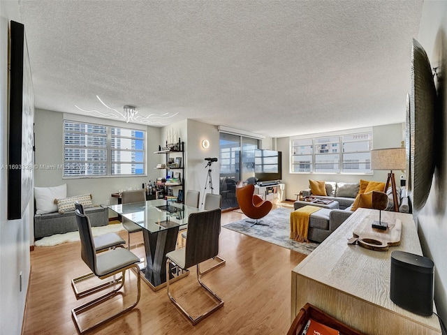 dining area with light hardwood / wood-style floors and a textured ceiling