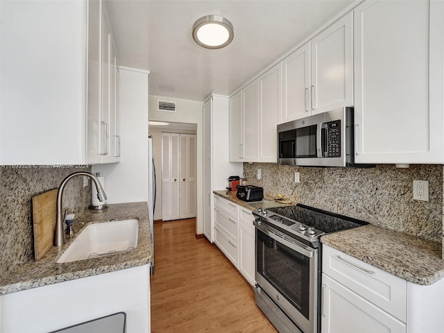 kitchen featuring stainless steel appliances, light hardwood / wood-style floors, white cabinetry, and sink