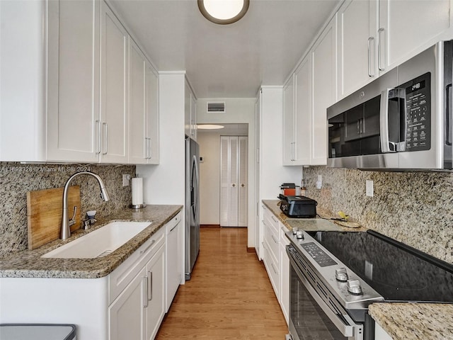 kitchen featuring light hardwood / wood-style flooring, light stone countertops, appliances with stainless steel finishes, and white cabinets