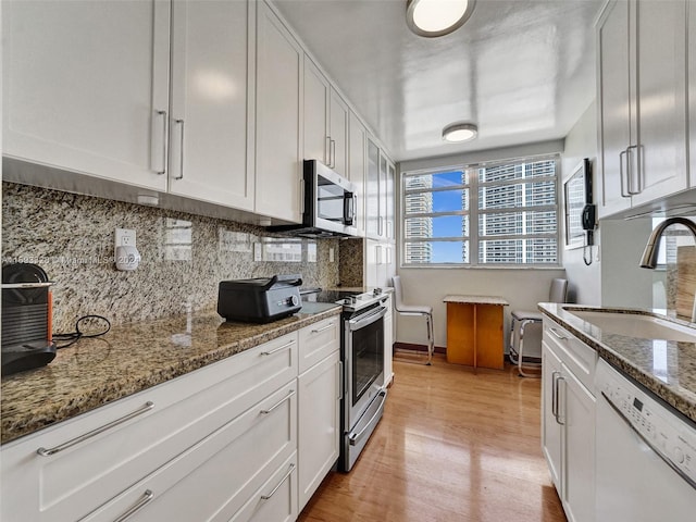 kitchen featuring dark stone counters, white cabinetry, appliances with stainless steel finishes, and light hardwood / wood-style flooring