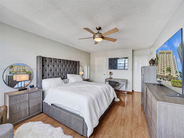 bedroom with a textured ceiling, ceiling fan, and light hardwood / wood-style flooring