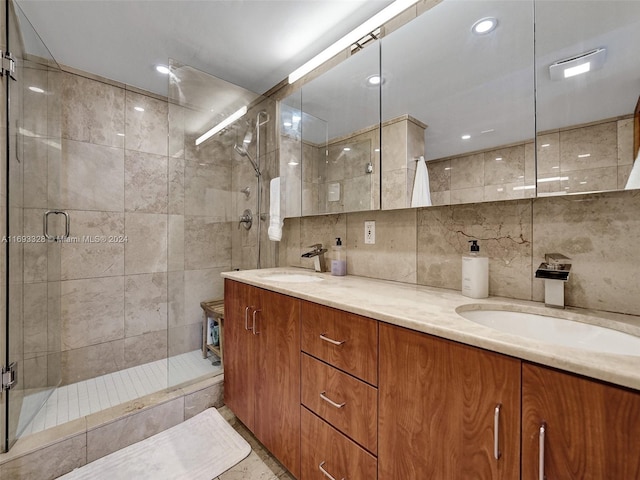 bathroom featuring tile walls, backsplash, vanity, and a shower with shower door