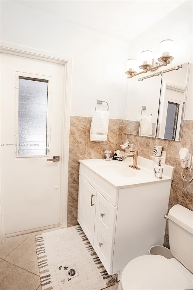 bathroom featuring toilet, vanity, tile walls, and tile patterned floors