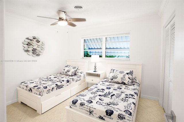 bedroom featuring light tile patterned flooring, ceiling fan, a closet, and ornamental molding