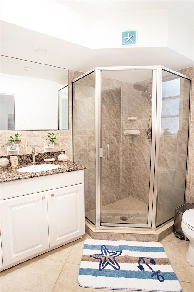 bathroom with backsplash, vanity, a shower with shower door, tile patterned floors, and toilet