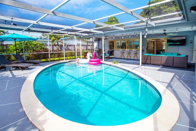 view of swimming pool with glass enclosure, an outdoor living space, a patio, and ceiling fan