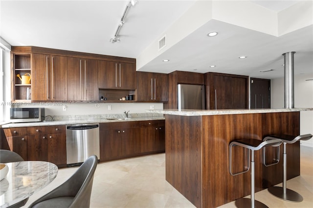 kitchen with rail lighting, a center island, dark brown cabinetry, and stainless steel appliances