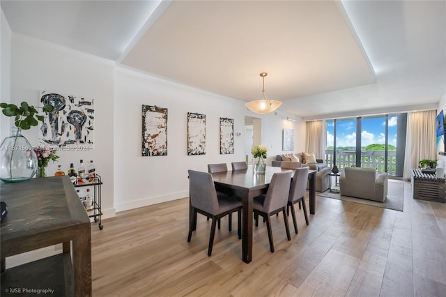 dining area featuring light wood-type flooring and a wall of windows