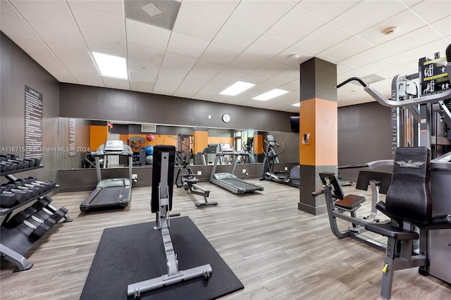 workout area featuring light wood-type flooring and a drop ceiling