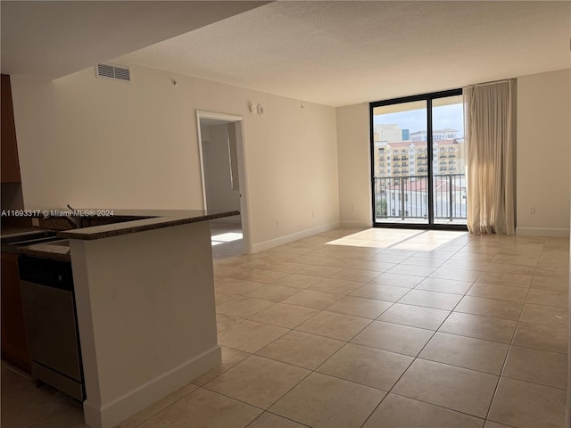 spare room with expansive windows, a textured ceiling, and light tile patterned floors