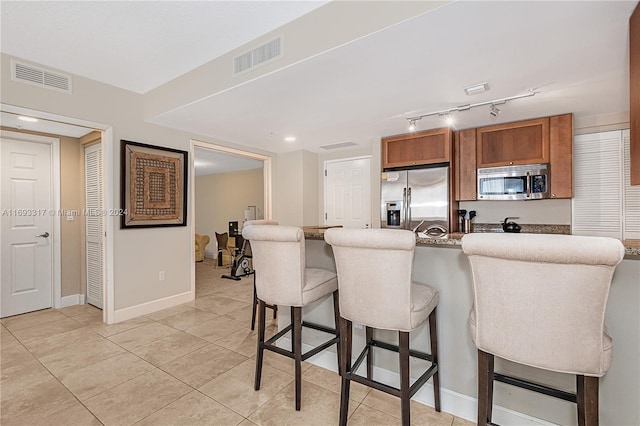 kitchen with appliances with stainless steel finishes, a breakfast bar area, and light tile patterned floors