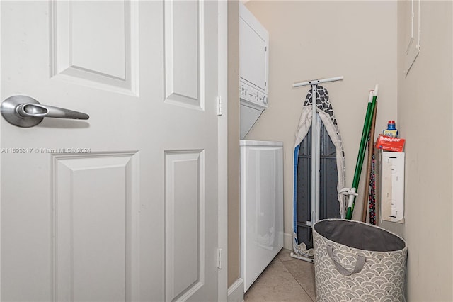 clothes washing area with light tile patterned floors and stacked washer / dryer