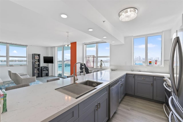 kitchen with stainless steel appliances, sink, kitchen peninsula, gray cabinetry, and light wood-type flooring