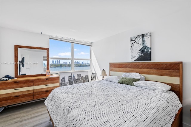 bedroom featuring wood-type flooring and a water view