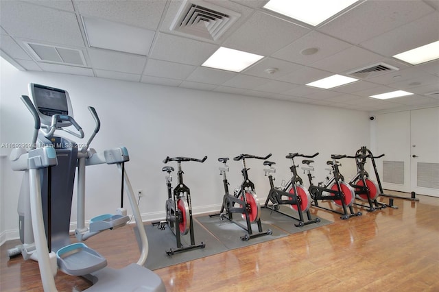 exercise room featuring wood-type flooring and a drop ceiling