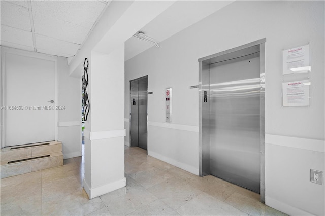 bathroom with a drop ceiling, elevator, and tile patterned flooring