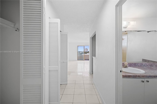 hallway featuring sink, light tile patterned floors, and a textured ceiling