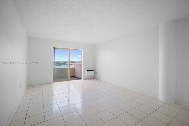 tiled spare room featuring a textured ceiling and heating unit