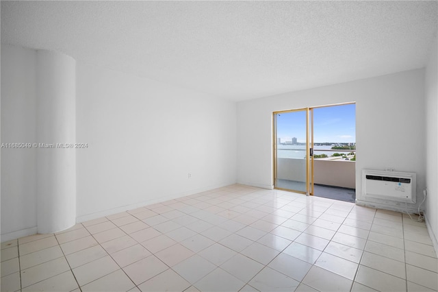 tiled spare room with a water view, a textured ceiling, and heating unit