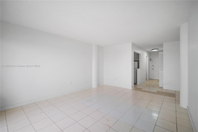 empty room with a textured ceiling and light tile patterned flooring