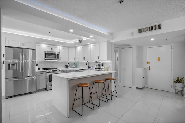 kitchen with decorative backsplash, white cabinetry, appliances with stainless steel finishes, and sink