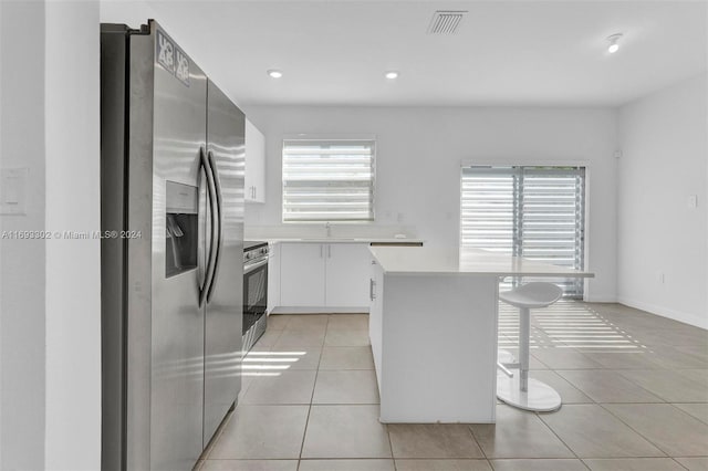 kitchen featuring light tile patterned floors, stainless steel appliances, white cabinetry, and a wealth of natural light