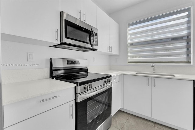 kitchen featuring white cabinets, light tile patterned floors, stainless steel appliances, and sink