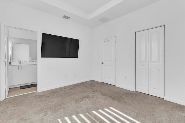 unfurnished bedroom featuring light colored carpet and ensuite bathroom