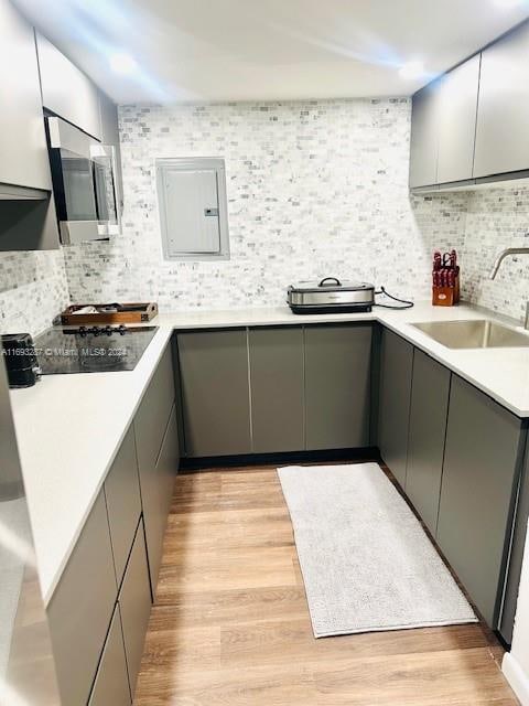 kitchen with gray cabinets, light hardwood / wood-style floors, sink, and decorative backsplash