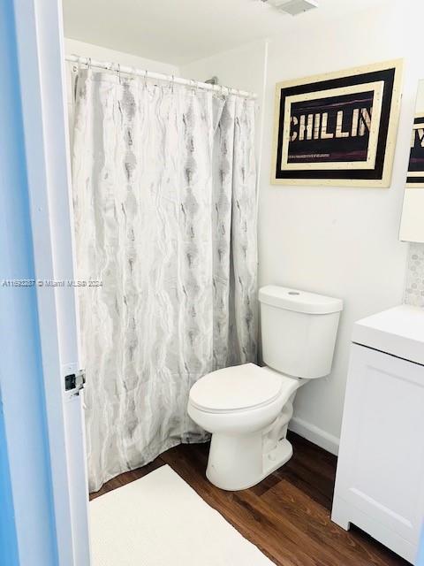 bathroom featuring a shower with curtain, wood-type flooring, vanity, and toilet