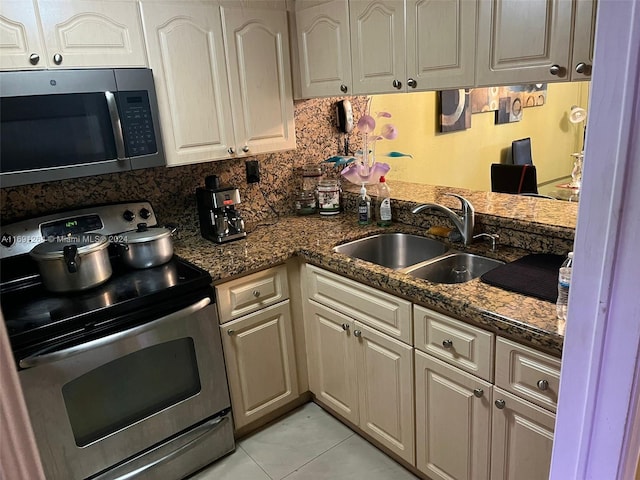 kitchen with dark stone counters, appliances with stainless steel finishes, sink, and light tile patterned floors