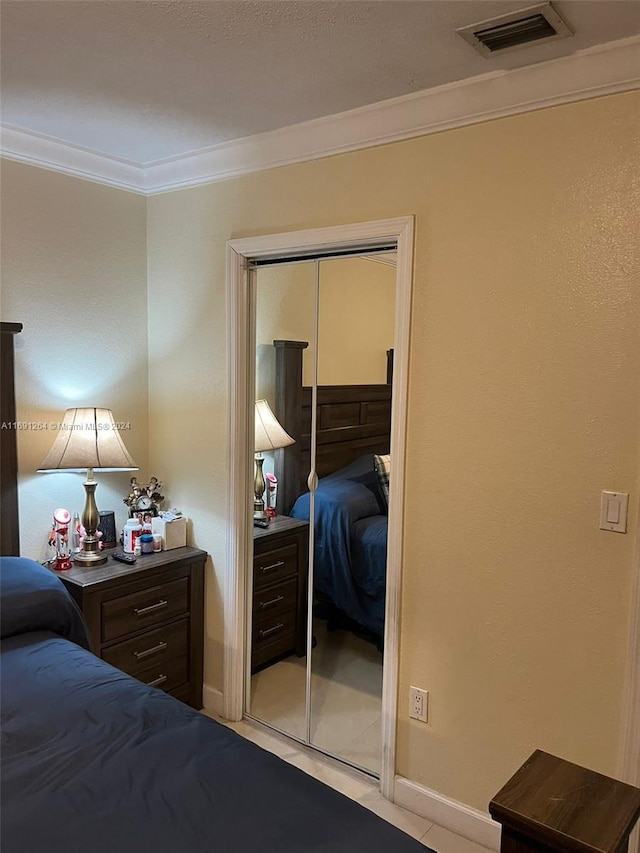 tiled bedroom with crown molding and a closet