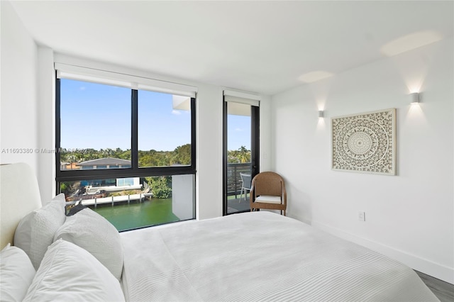 bedroom with a water view and hardwood / wood-style floors