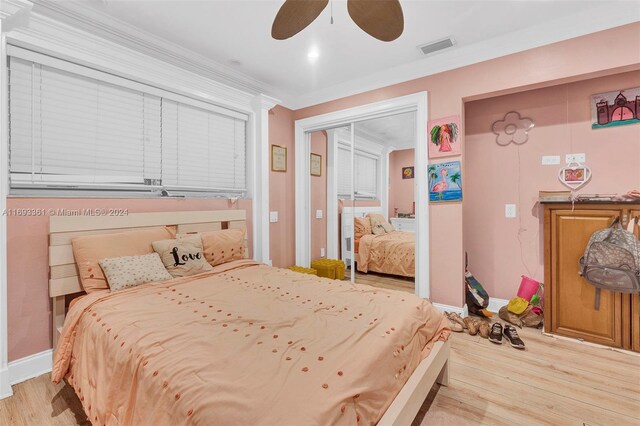 bedroom featuring a closet, light hardwood / wood-style floors, ceiling fan, and ornamental molding