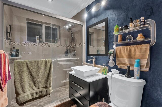 bathroom featuring hardwood / wood-style floors, toilet, a shower with door, vanity, and ornamental molding