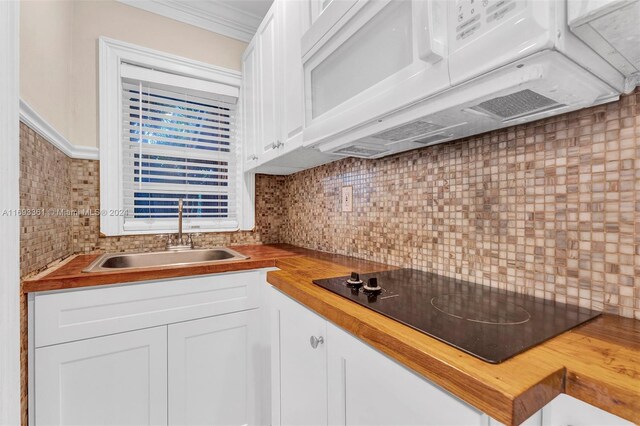 kitchen with wood counters, decorative backsplash, black electric cooktop, sink, and white cabinets