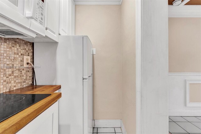 kitchen with decorative backsplash, light tile patterned flooring, white appliances, and white cabinetry