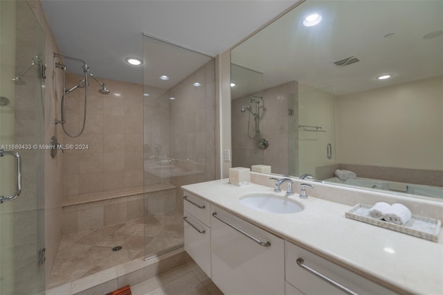 bathroom with a shower with door, vanity, and tile patterned flooring