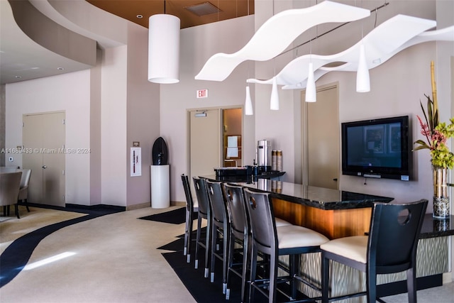 bar featuring concrete flooring, a towering ceiling, and hanging light fixtures