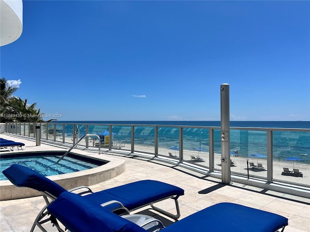 exterior space featuring a jacuzzi, a water view, and a view of the beach