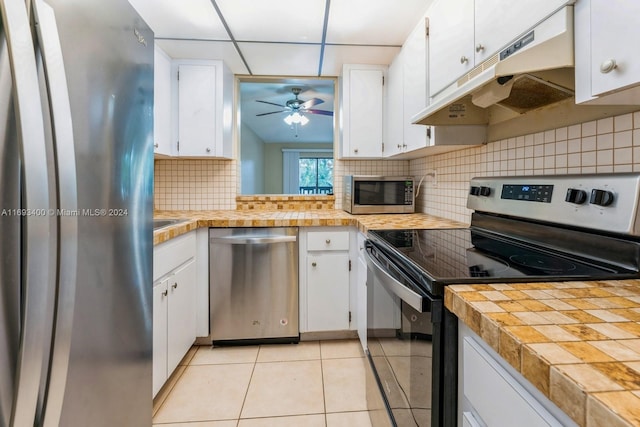 kitchen featuring appliances with stainless steel finishes, backsplash, white cabinetry, and light tile patterned flooring