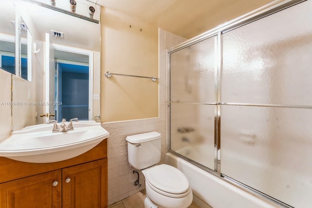 full bathroom featuring vanity, tile patterned flooring, toilet, enclosed tub / shower combo, and tile walls