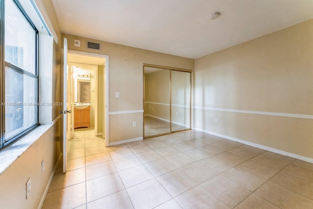 unfurnished bedroom featuring light tile patterned floors and a closet